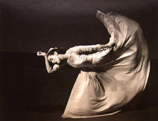 A woman kicks a long skirt high behind her