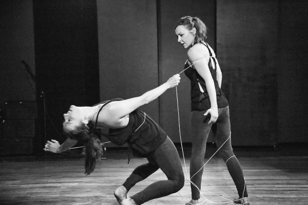 A dancer bends back away from a standing dancer