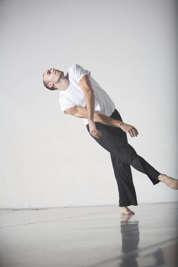 A dancer crosses his arms and legs