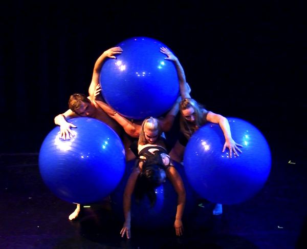 dancers hold three large bright blue balls