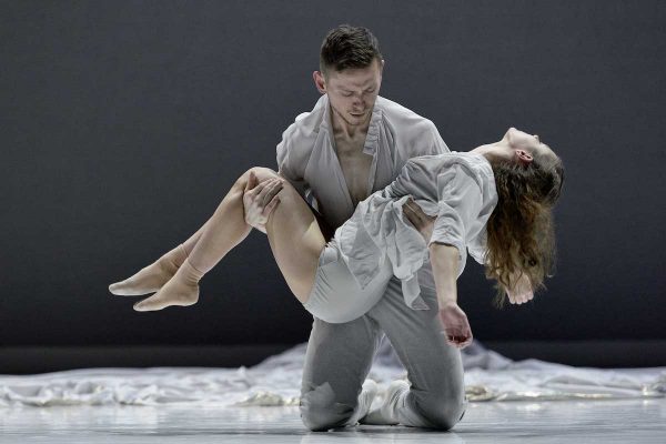 A male dancer kneels, cradling a woman in his arms