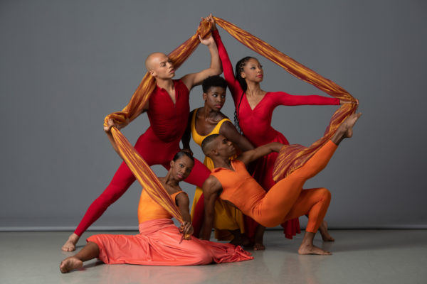 Dancers in orange and red extend scarves