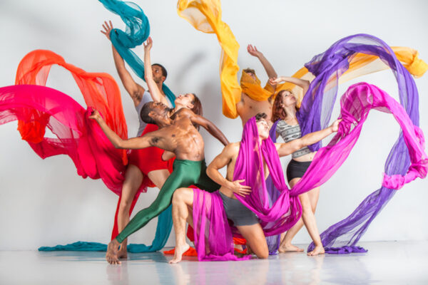 A group of dancers toss colorful scarves