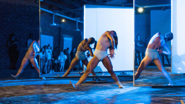dancers in white trunks cover their faces