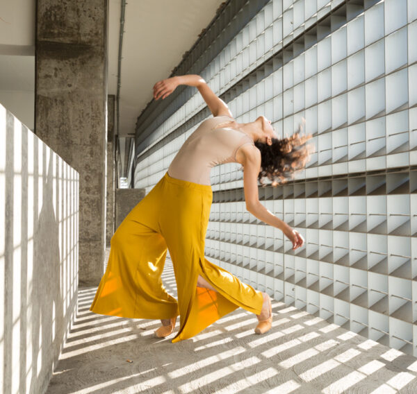 A woman in yellow coulottes bends backward
