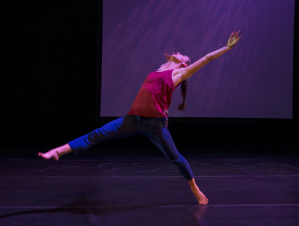 A dancer in blue tights and red top 