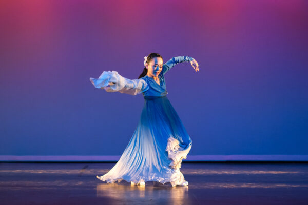 A woman dances in a blue dress