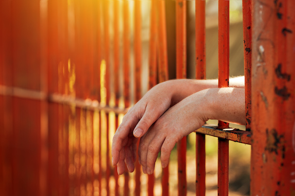 Image of a pair of hands resting on a red fence.