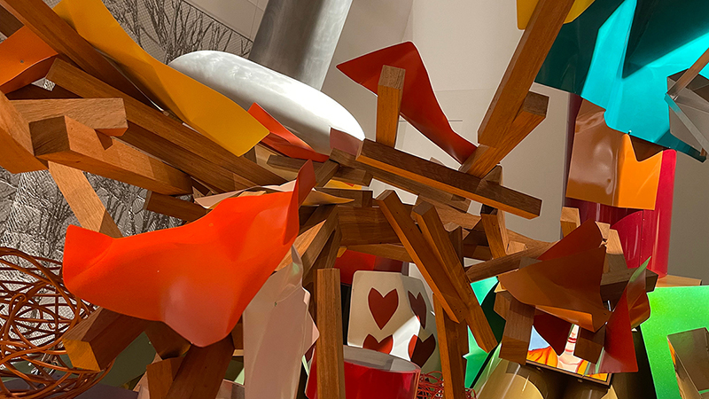 Pieces of wood and abstracts shapes full of color converge in mid-air.