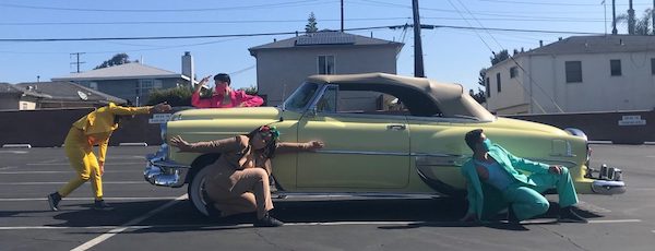 Three dancers pose around a vintage chartreuse convertible in a dance celebrating the lowrider culture.
