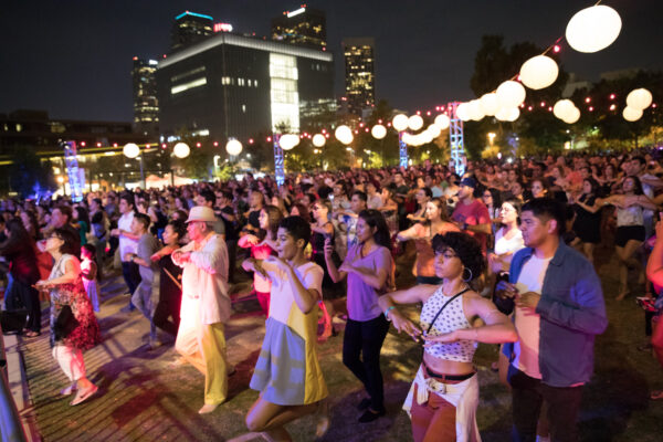 A large group of people dance together at night.