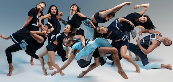 A group of ten dancers, most in black, strike different poses