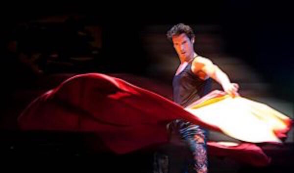 A male flamenco dancer twirls a cape