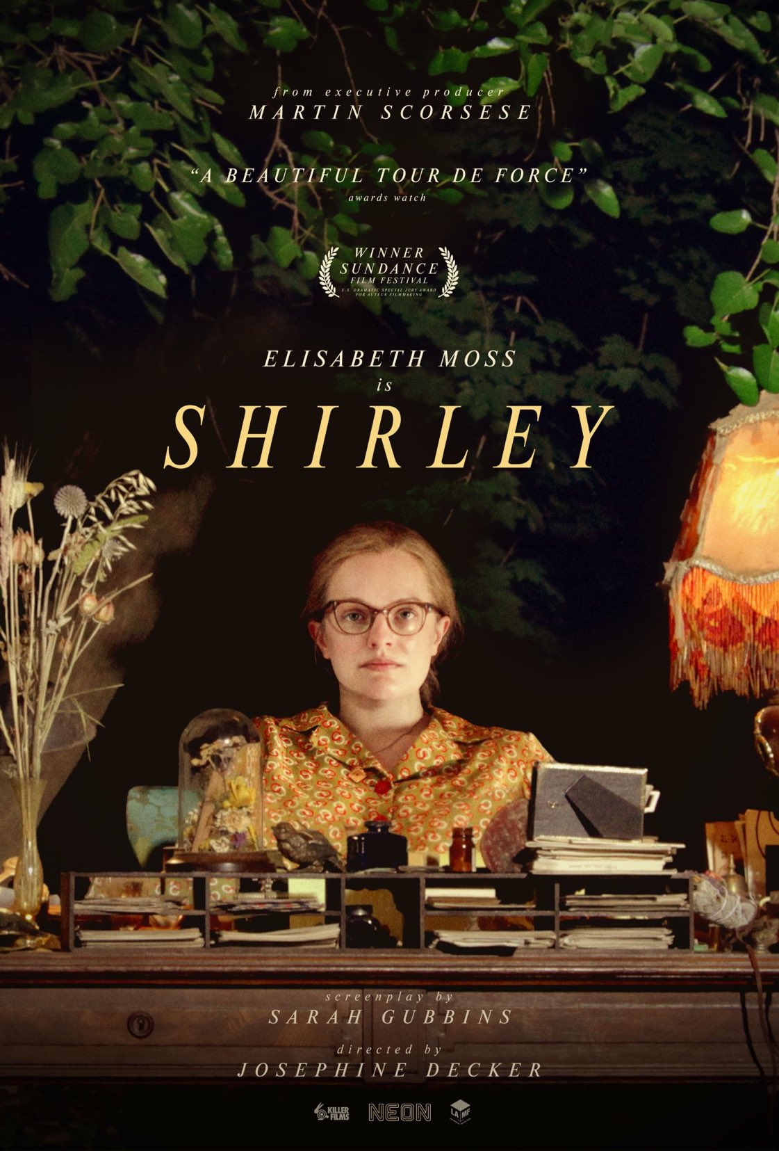 Poster for a film titled Shirley depicting the actress Elizabeth Moss sitting at her desk surrounded by plants, pill and alcohol bottles, typewriter and darkness.