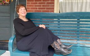 A woman in a long black dress and cowboy boots