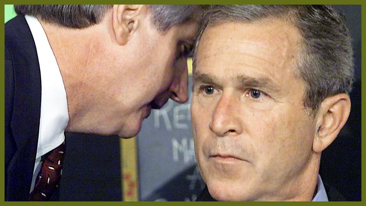 A shocked and confused look on George W Bush's face as a man whispers in his ear.