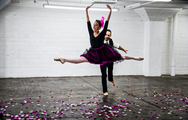a dancer leaps across floor of flowers