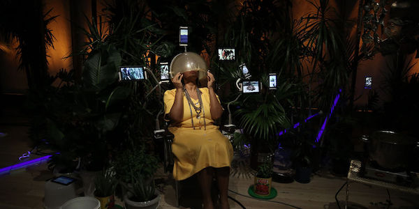 Woman in yellow dress sitting with round globe on her head