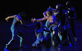 A man in blue lights lunges toward a group stretching a hand toward him
