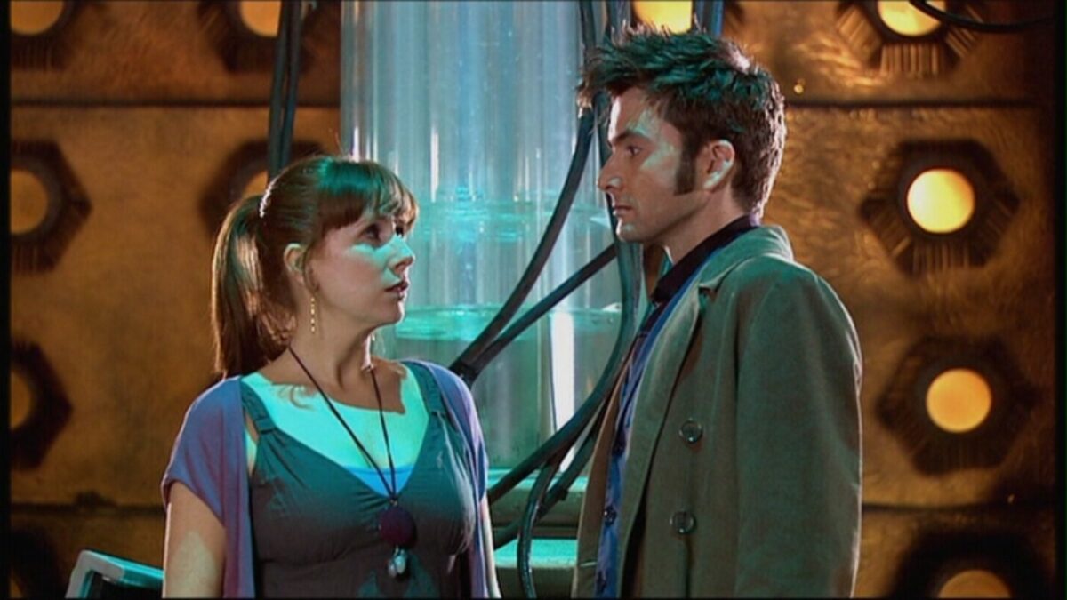 Two people, Doctor Who and Donna, look concerned as they stand together.