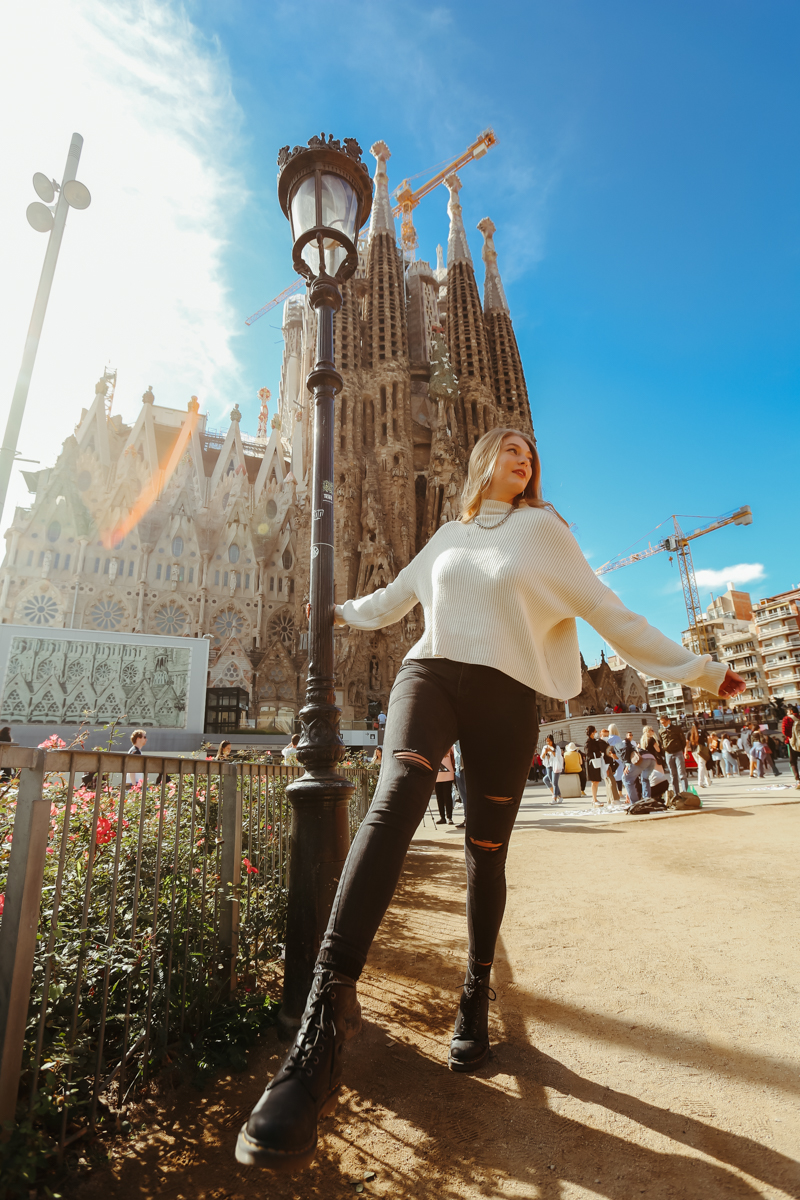 A young blonde woman poses in front of the Sagrada Familia in Barcelona