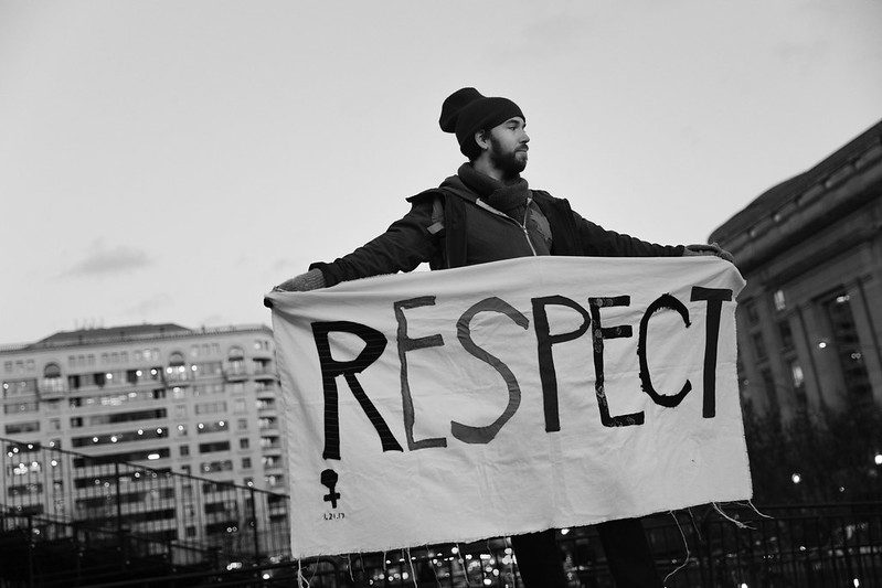a black and white photo of a man holding up a sign that says RESPECT