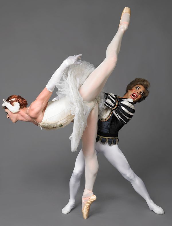 A male dancer holds the swan queen, her leg just missing his head