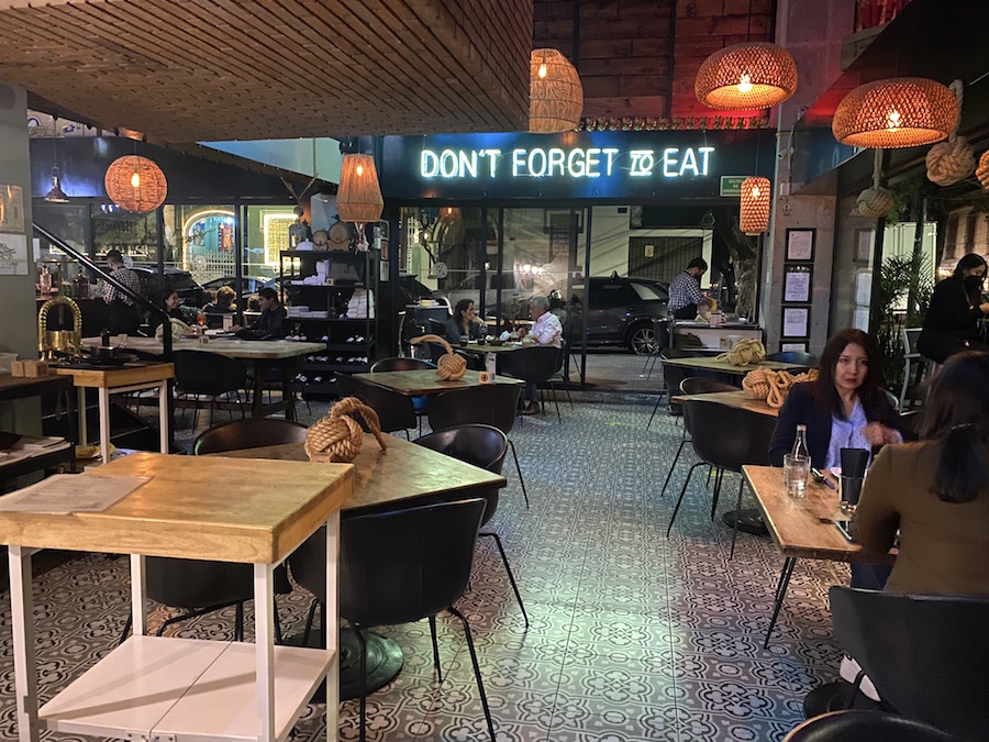 The main floor of the restaurant, Nudo Negro, showing a large neon sign: DON'T FORGET TO EAT