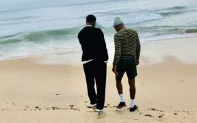 Two Black men walking on the beach.