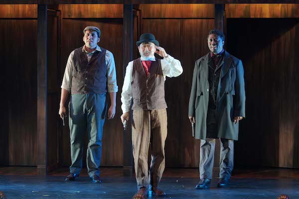 Three actors face the audience with guns in Assassins.