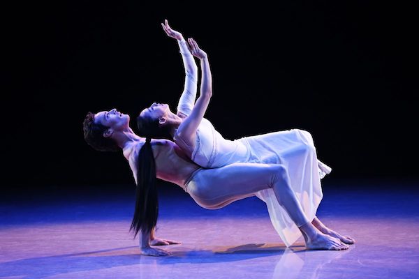 A woman in white bends back against a man