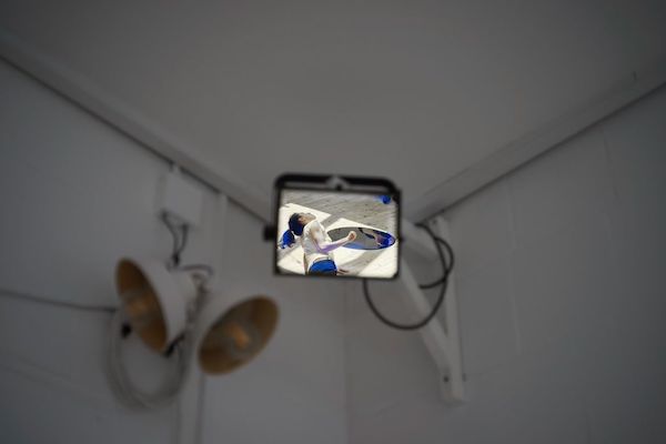 A security camera in a wall shows a dancer