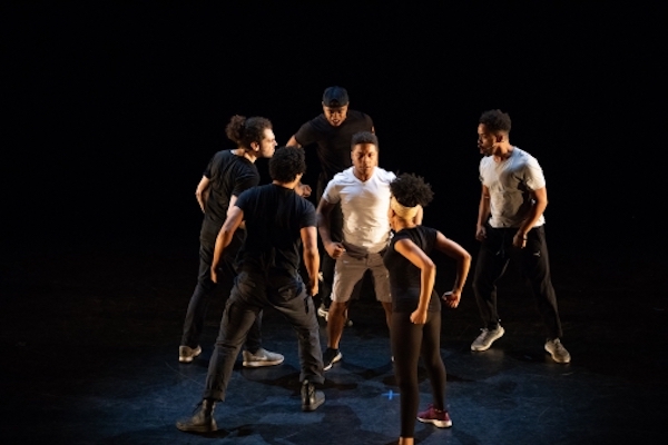 A man in a white t-shirt is surrounded by five other dancers