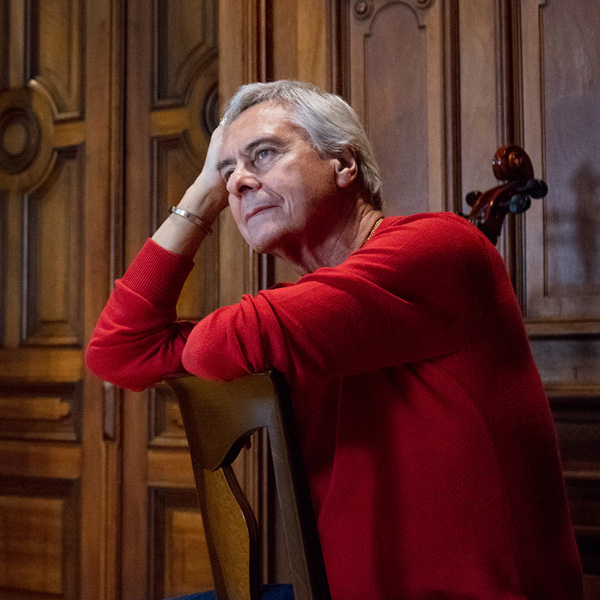 John Neumeier in a red sweater looks thoughtful
