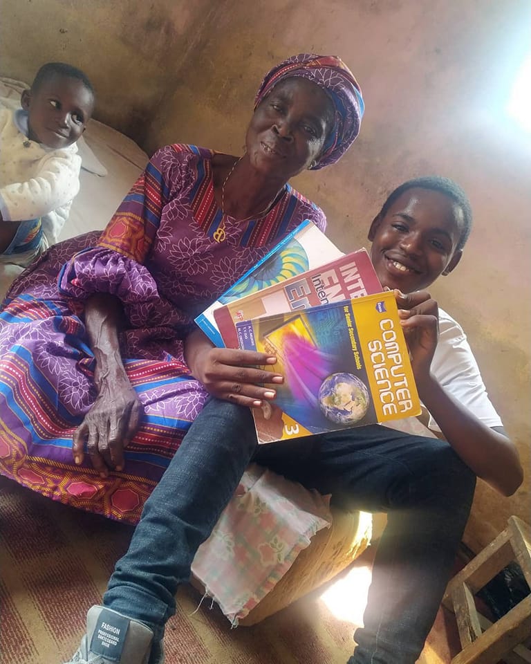 happy mother and child, who is holding up books he borrowed at The Yellow House library