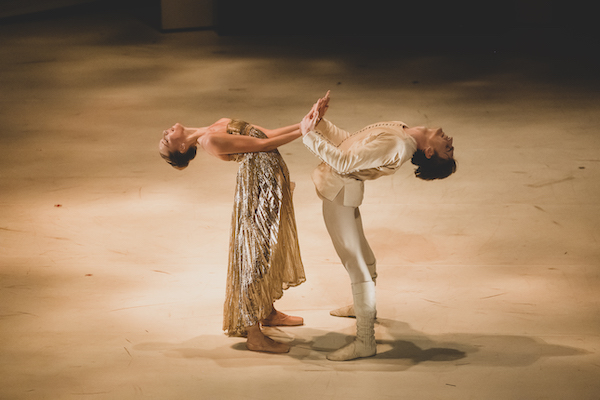 Two dancers hold hands and bend backwards