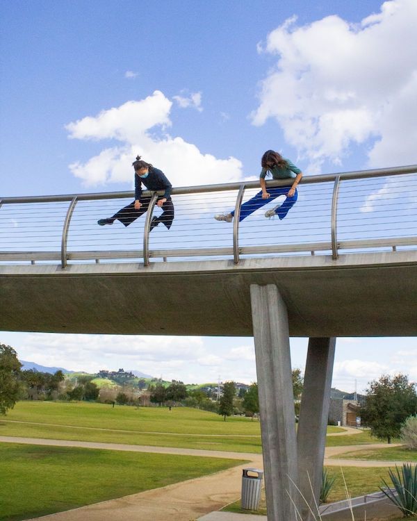 Two dancers draped over a freeway overpass