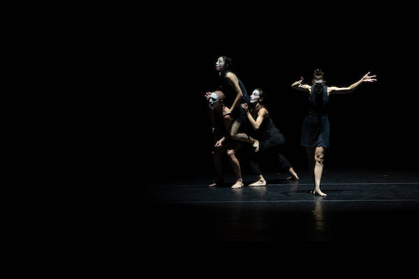 Four dancers on a darkened stage