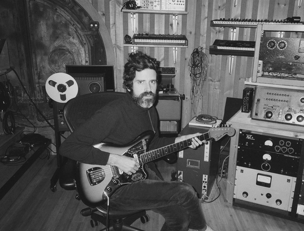 Singer Devendra Banhart shown in his studio holding a guitar