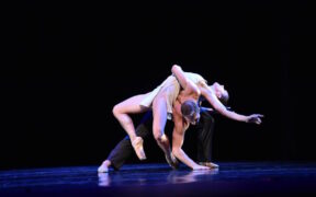 A dancer bends back across her partner's back