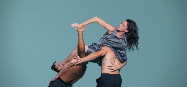 Two male dancers lift a female dancer in blue