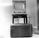 a black and white photo of an old 50s style TV set on a black TV stand