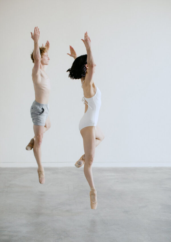Two dancers in white jump up