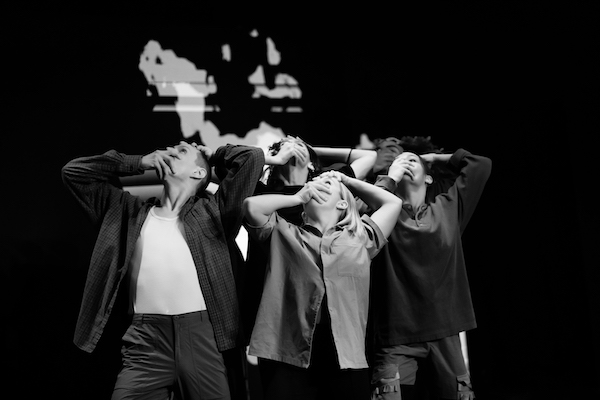 Dancers look up with hands covering their faces