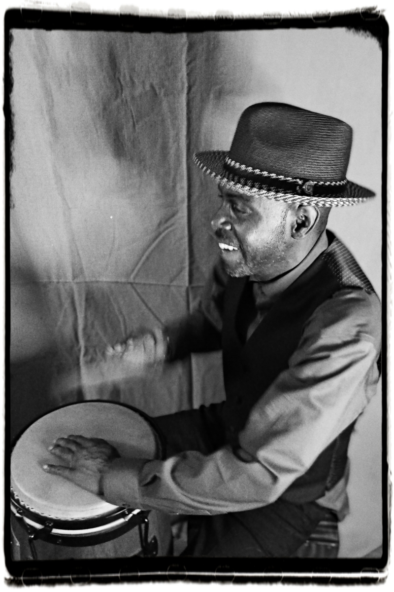 black and white photo of poet, performer, neo-griot A.K. Toney playing the drum