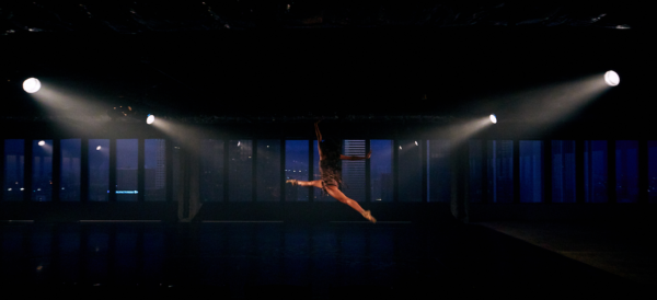 A dancer leaps amid four spotlights