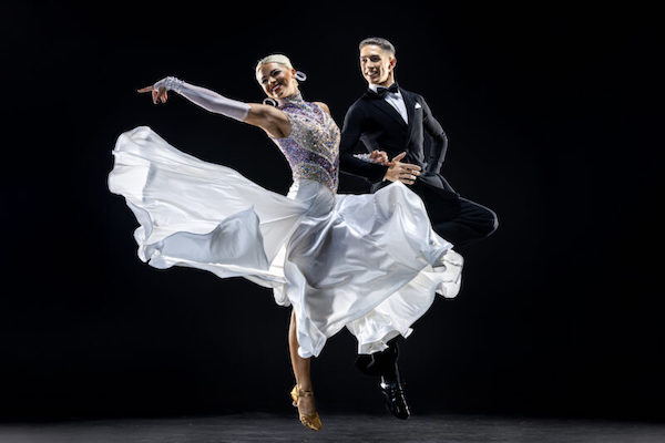 A woman in a floaty white dress dances with a man in formal wear