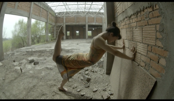 A dancer leans against a building
