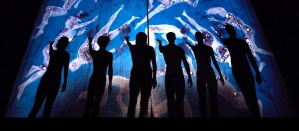 A group stands in front of blue lit scrim