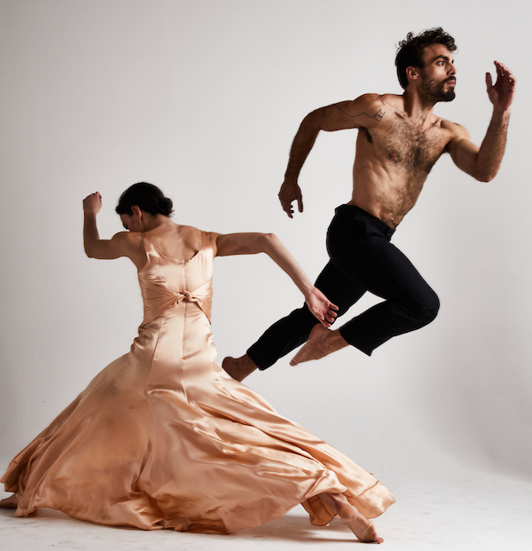 A woman in a long pink dress and a bare chested man jumping
